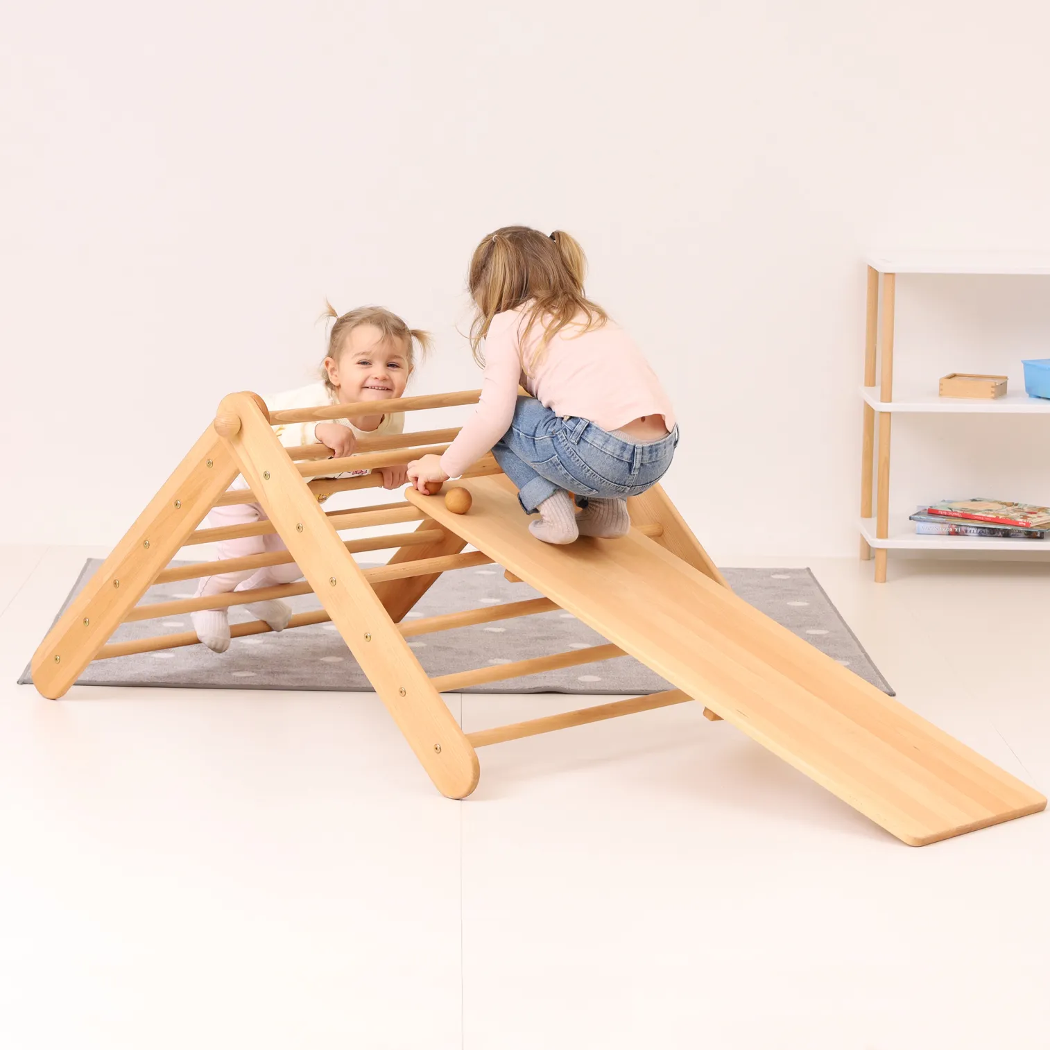 Toddler climbing on CLIMBIE wooden triangle with stone ramp in a Montessori-inspired play corner